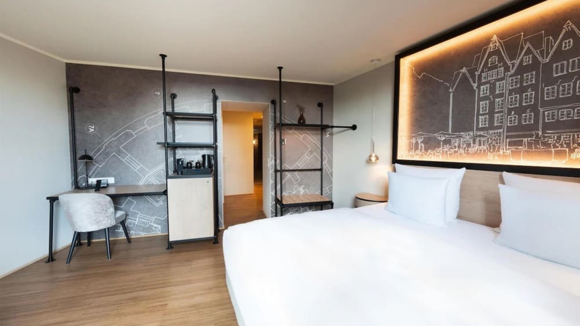 King bed with white linens, wall art headboard, and narrow windowed corridor leading to separate seating area
