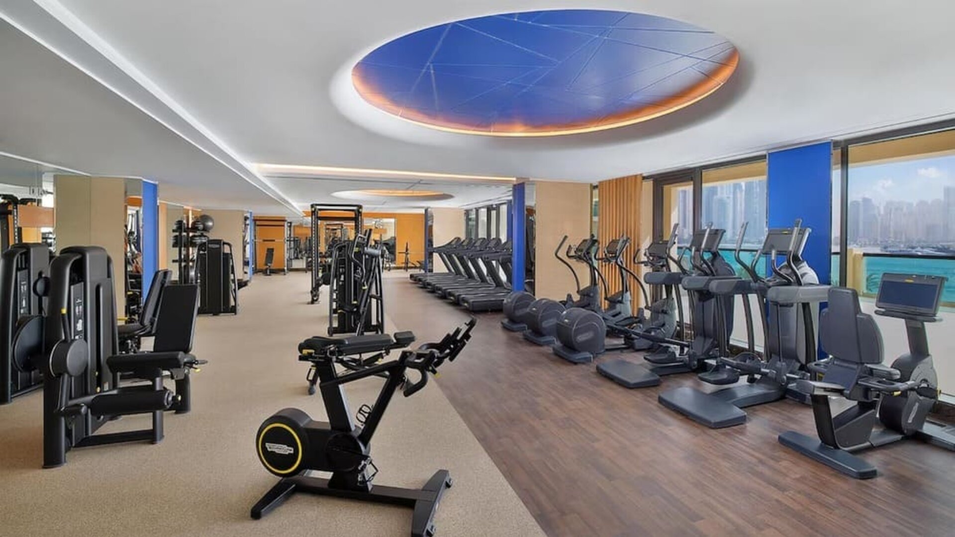 Spacious fitness center with cardio machines, weight equipment, and large windows facing the water