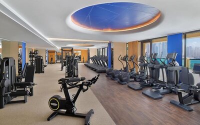 Spacious fitness center with cardio machines, weight equipment, and large windows facing the water