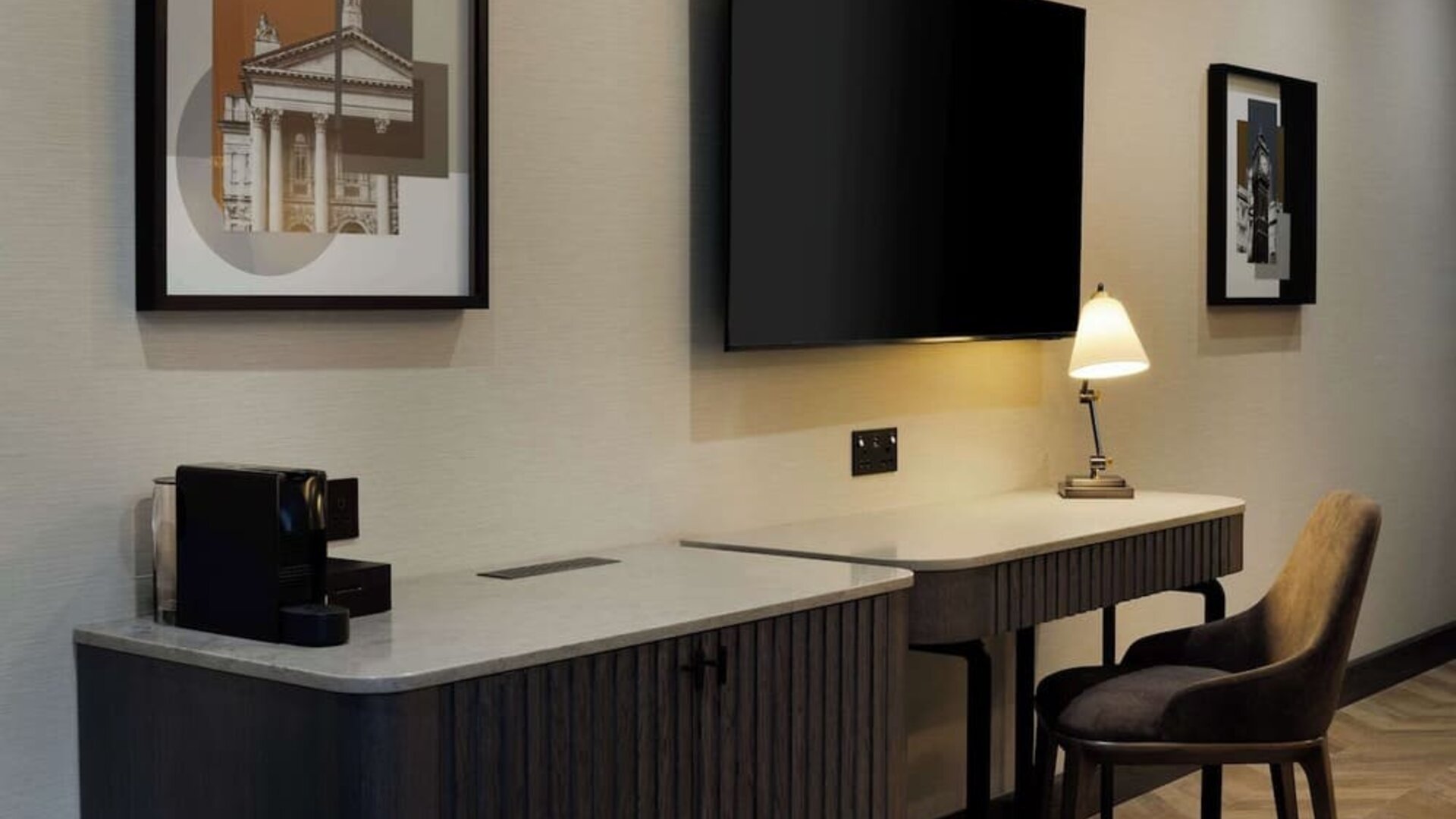 Work desk area with marble countertop, wall-mounted TV, desk lamp, and upholstered chair