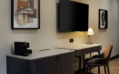 Work desk area with marble countertop, wall-mounted TV, desk lamp, and upholstered chair