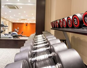 Fitness center with free weights, mirrored wall, and cardio machines in the background