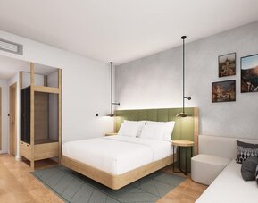 King guest room with green upholstered headboard, wood accents, pendant lights, and small sofa