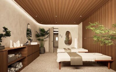 Spa treatment room with two massage tables, wood-paneled walls, candles, and indoor plants