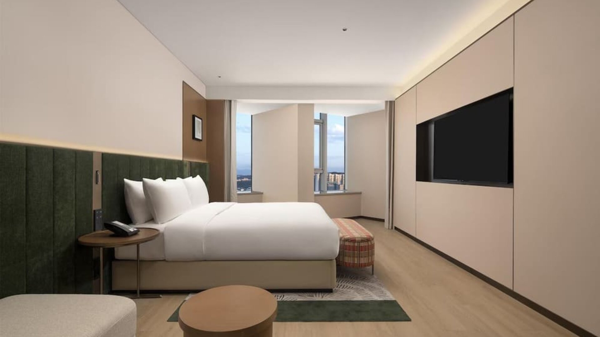 King bedroom with mountain and city views through corner windows, chaise lounge, and patterned bench