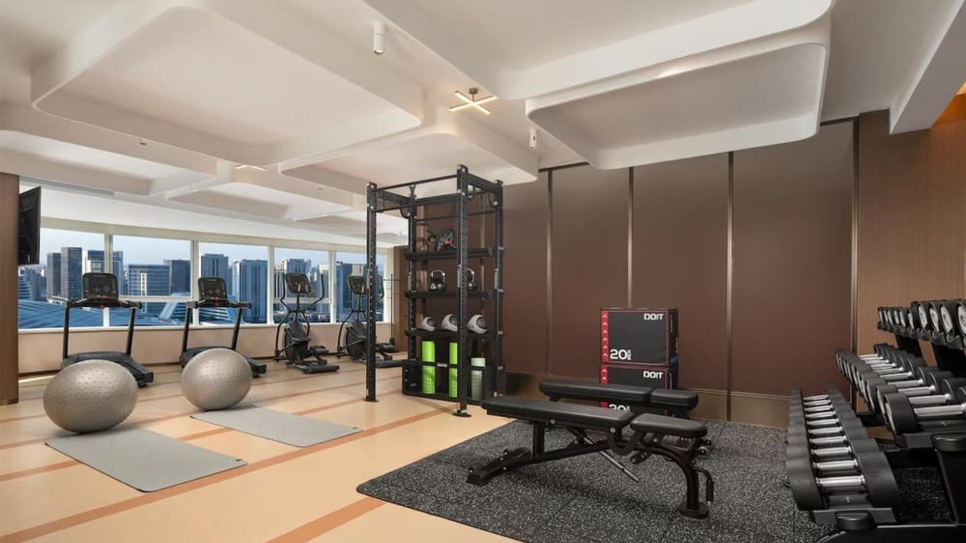 Fitness center with treadmills, free weights, workout bench, yoga mats, and floor-to-ceiling windows