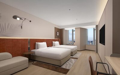 Modern double room with two beds, orange headboards, seating area, and floor-to-ceiling windows