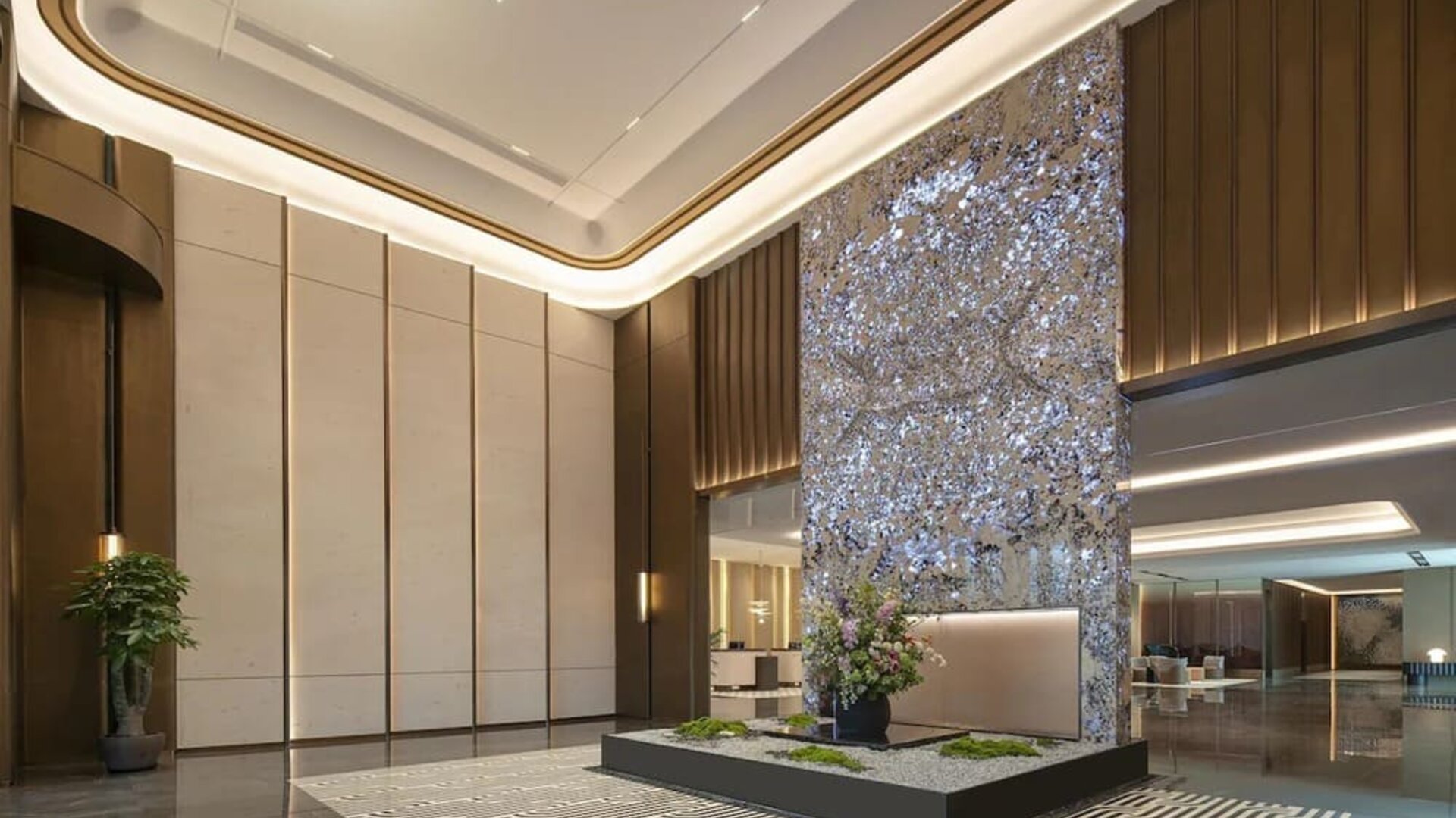 Grand reception lobby with tall decorative art wall, polished floors, and warm accent lighting