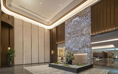 Grand reception lobby with tall decorative art wall, polished floors, and warm accent lighting