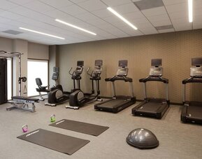 Gym area featuring cardio machines, yoga mats, kettlebells, and functional workout equipment at Courtyard By Marriott Los Angeles LAX/Century Boulevard.
