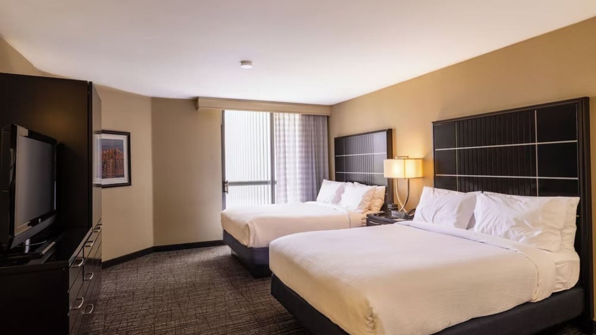 Double queen guest room with two beds, modern décor, and large window at Embassy Suites By Hilton LAX Airport North.