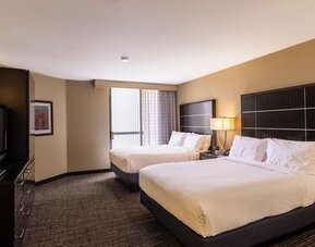 Double queen guest room with two beds, modern décor, and large window at Embassy Suites By Hilton LAX Airport North.
