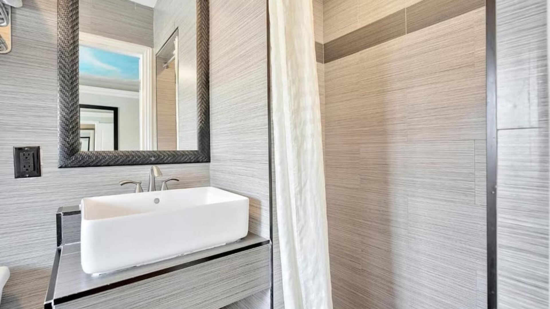 Contemporary bathroom with modern sink vanity, textured wall tiles, and walk-in shower at Mid City Inn - Los Angeles.