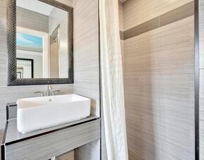 Contemporary bathroom with modern sink vanity, textured wall tiles, and walk-in shower at Mid City Inn - Los Angeles.