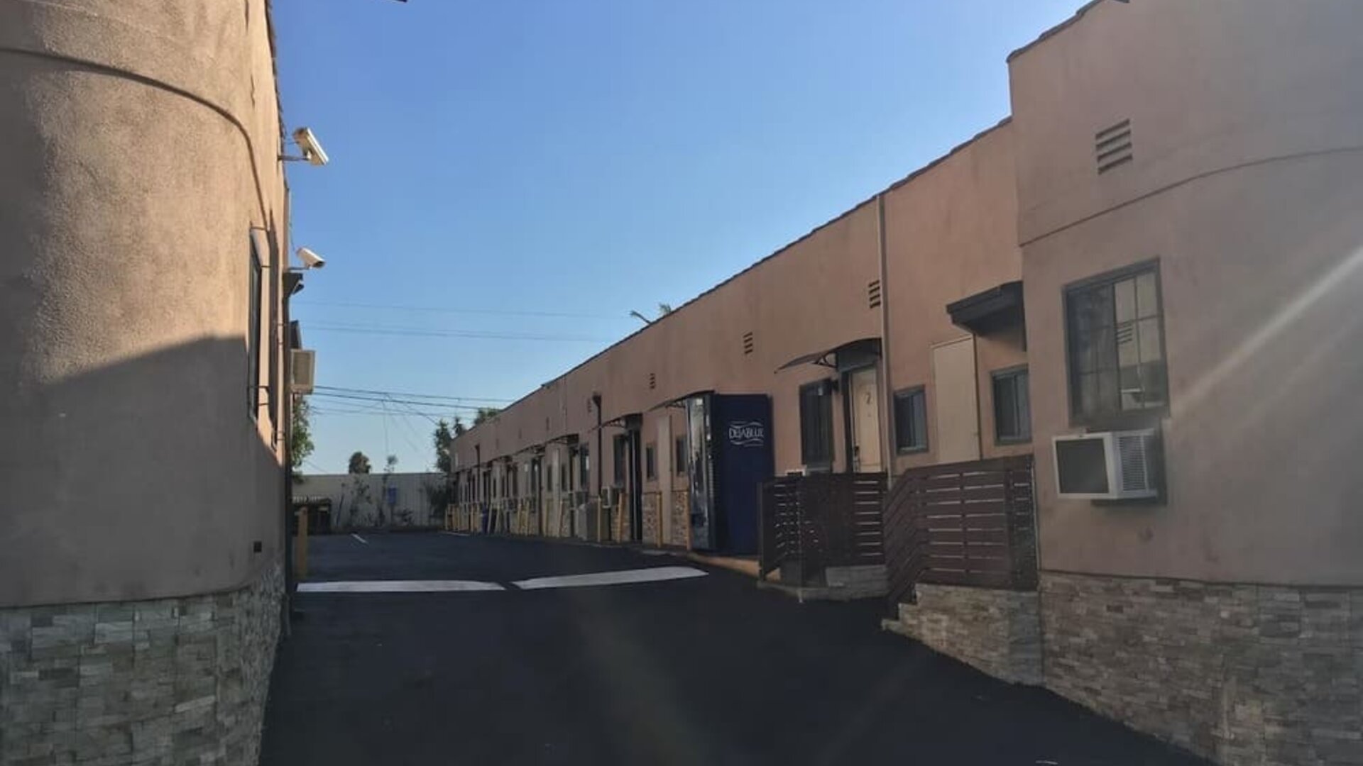 Exterior driveway view showing motel-style room entrances and parking access at Mid City Inn - Los Angeles.