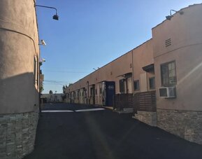 Exterior driveway view showing motel-style room entrances and parking access at Mid City Inn - Los Angeles.