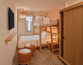 Guest room with two beds, modern headboard, and balcony seating area at The Ambassador Hotel Of Waikiki.