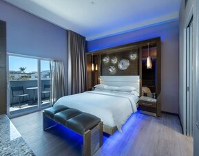 Spacious king room with blue accent lighting, balcony access, and modern wood finishes at Shade Hotel Manhattan Beach.