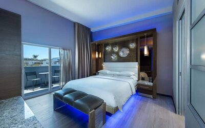 Spacious king room with blue accent lighting, balcony access, and modern wood finishes at Shade Hotel Manhattan Beach.