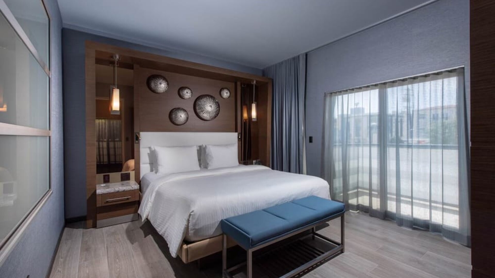 Contemporary king room with balcony doors, bench seating, and floor-to-ceiling curtains at Shade Hotel Manhattan Beach.