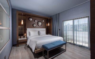 Contemporary king room with balcony doors, bench seating, and floor-to-ceiling curtains at Shade Hotel Manhattan Beach.