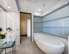 Contemporary bathroom with freestanding soaking tub, pebble flooring, and frosted glass wall panels at Shade Hotel Manhattan Beach.
