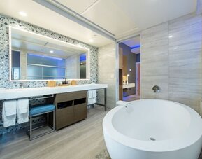 Spacious bathroom with freestanding tub, large vanity mirror, and mosaic accent wall at Shade Hotel Manhattan Beach.