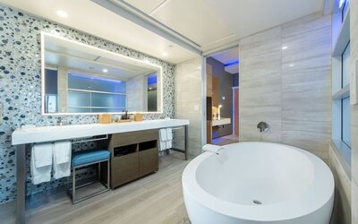 Spacious bathroom with freestanding tub, large vanity mirror, and mosaic accent wall at Shade Hotel Manhattan Beach.