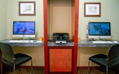Business center with two desktop computers, printer station, and granite work counters at Shade Hotel Manhattan Beach.