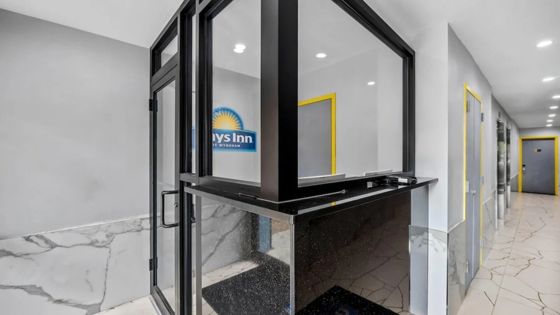 Modern reception desk area with marble-style flooring and bright yellow door frames at Days Inn Chinatown NYC.