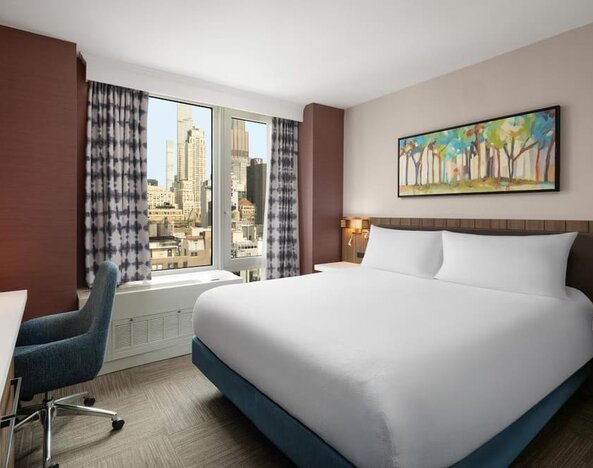 King bedroom with city views and workspace at Hilton Garden Inn New York/West 35th Street.