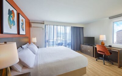 Modern king guest room with workspace and balcony at Courtyard Waikiki Beach.