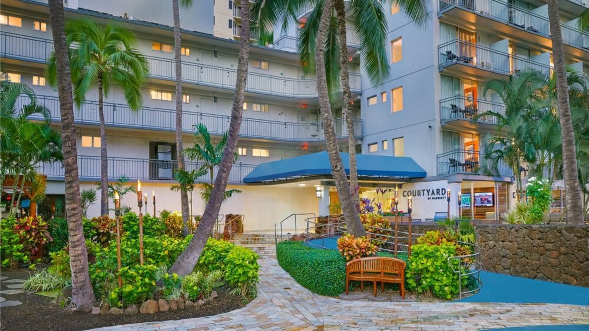 Tropical exterior entrance surrounded by palm trees at Courtyard Waikiki Beach.