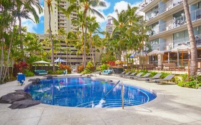 Outdoor swimming pool surrounded by palm trees at Courtyard Waikiki Beach.