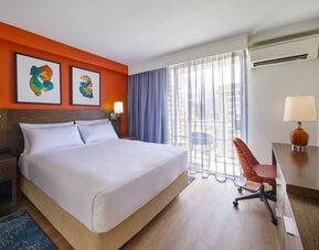 Bright king guest room with workspace and balcony access at Courtyard Waikiki Beach.