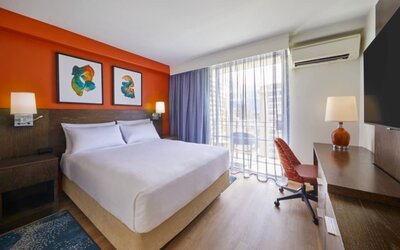 Bright king guest room with workspace and balcony access at Courtyard Waikiki Beach.