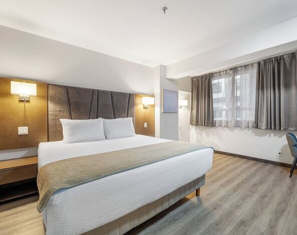 Bright king bedroom with comfortable bedding and workspace at Hotel Montreal Metropolitan, An Ascend Collection Hotel.