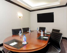 Private meeting room with conference table and presentation screen at Courtyard By Marriott New York JFK Airport.