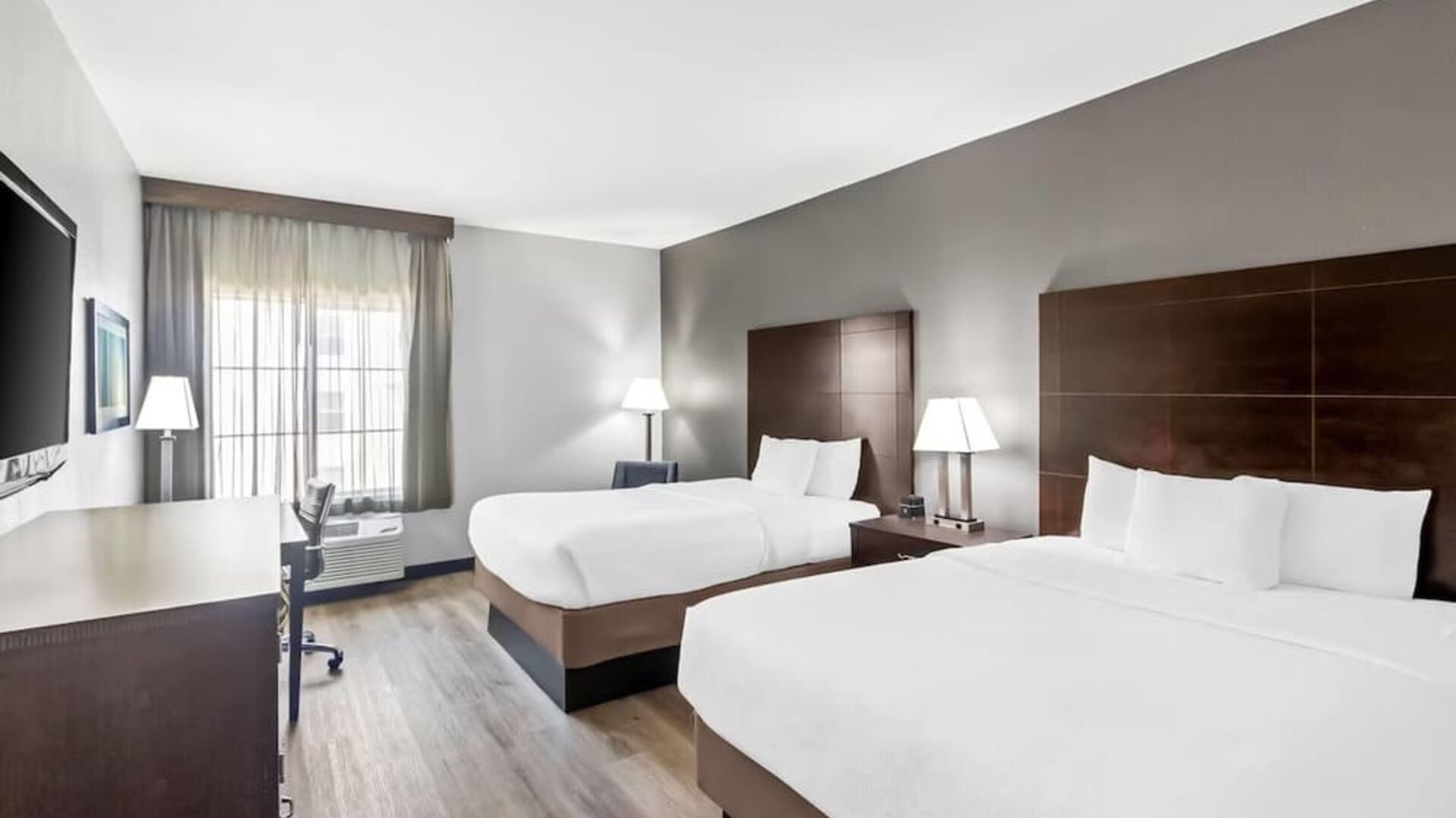 Spacious guest room with two beds, workspace, and large windows at La Quinta Inn & Suites By Wyndham Houston Energy Corridor.