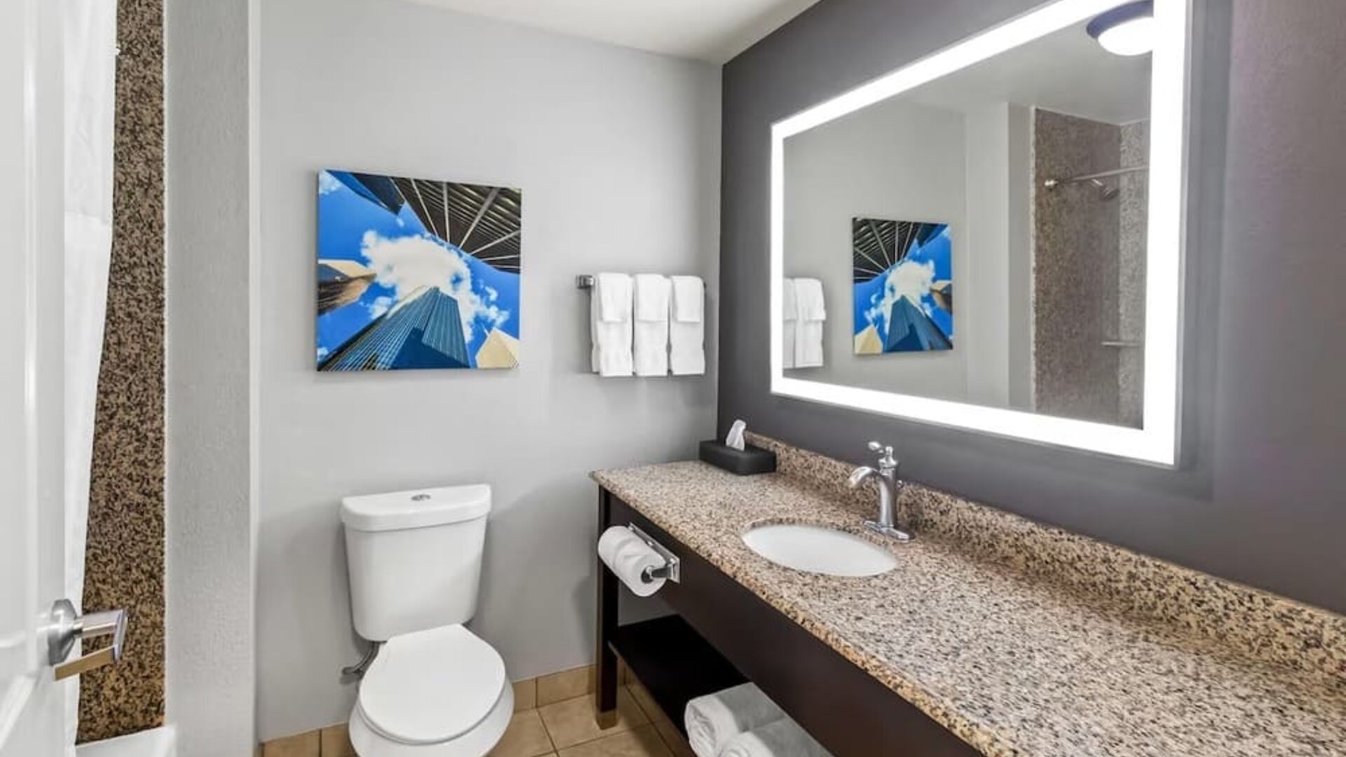 Modern bathroom with illuminated mirror and granite vanity at La Quinta Inn & Suites By Wyndham Houston Energy Corridor.