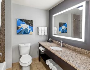 Modern bathroom with illuminated mirror and granite vanity at La Quinta Inn & Suites By Wyndham Houston Energy Corridor.