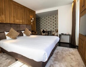 Spacious guest room with king bed, seating area, and television at Hôtel Espérance.