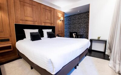 King bedroom with elegant wood finishes and seating nook at Hôtel Espérance.
