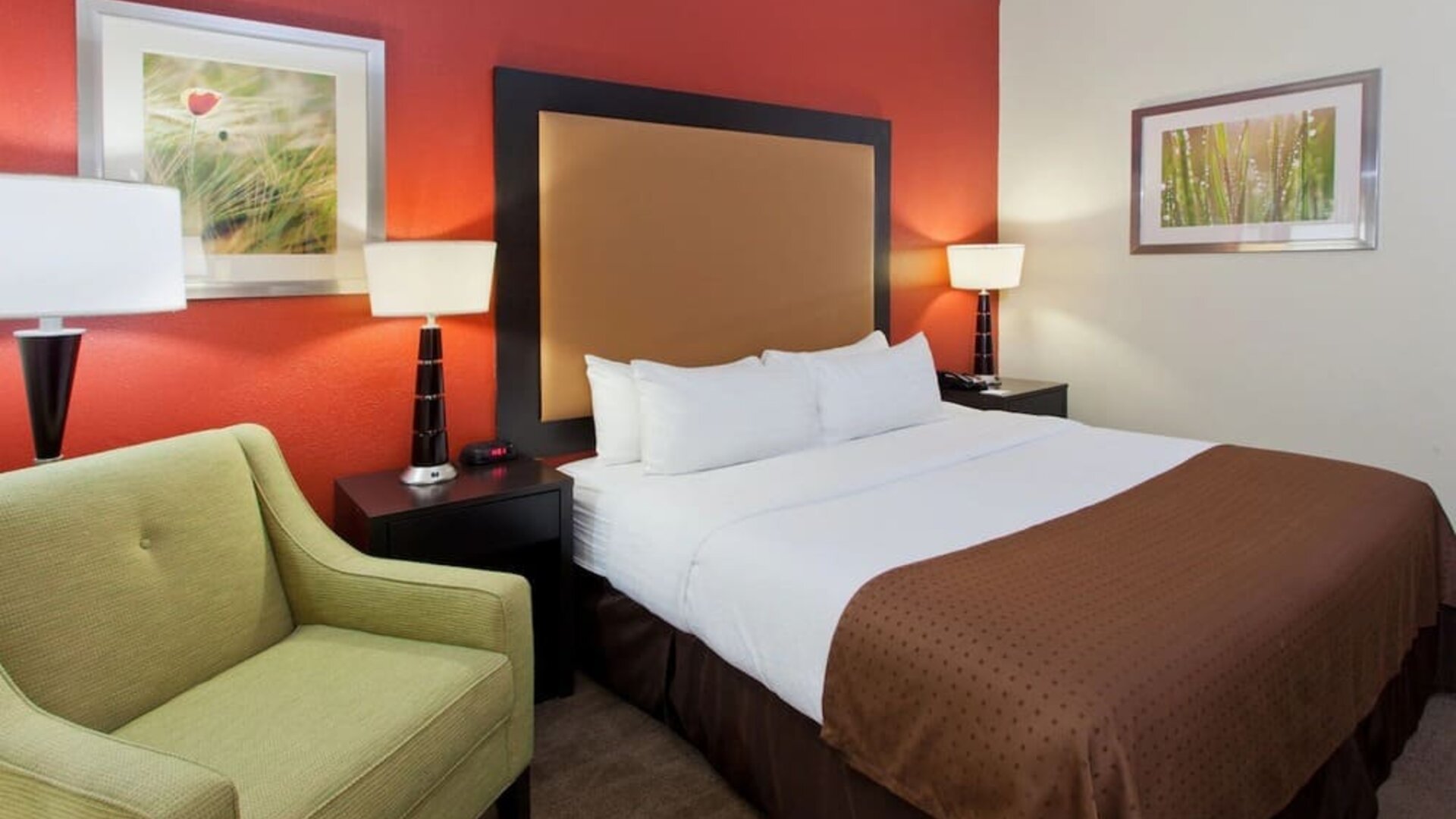 Guest room with king bed, lounge chair, and warm modern décor at Holiday Inn Downtown Shreveport.