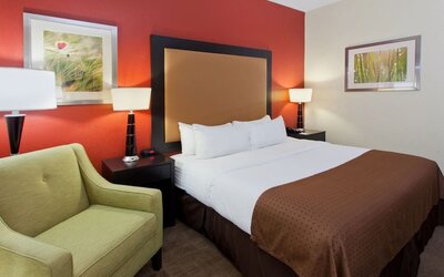 Guest room with king bed, lounge chair, and warm modern décor at Holiday Inn Downtown Shreveport.