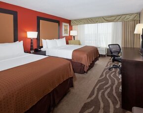 Large guest suite with two beds, sofa seating, and open floor plan at Holiday Inn Downtown Shreveport.