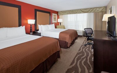 Large guest suite with two beds, sofa seating, and open floor plan at Holiday Inn Downtown Shreveport.