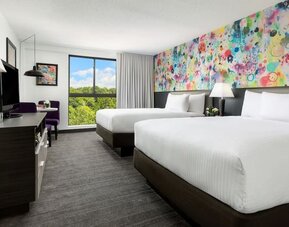 Double queen guest room with vibrant artistic décor and natural light at Hotel Studio Allston.