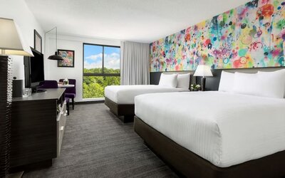 Double queen guest room with vibrant artistic décor and natural light at Hotel Studio Allston.