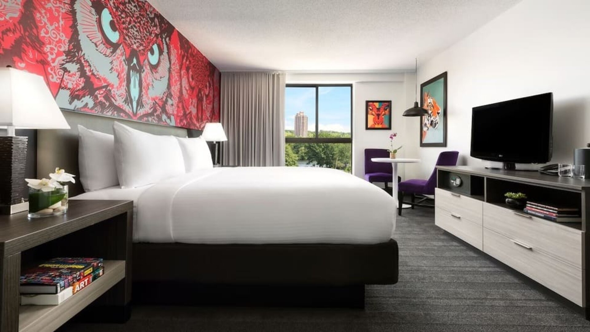 Contemporary guest room with large bed, modern décor, and scenic views at Hotel Studio Allston.